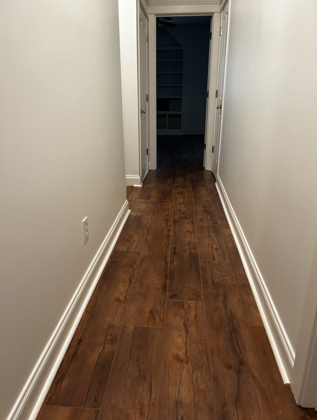 Narrow hallway with dark walnut laminate plank flooring