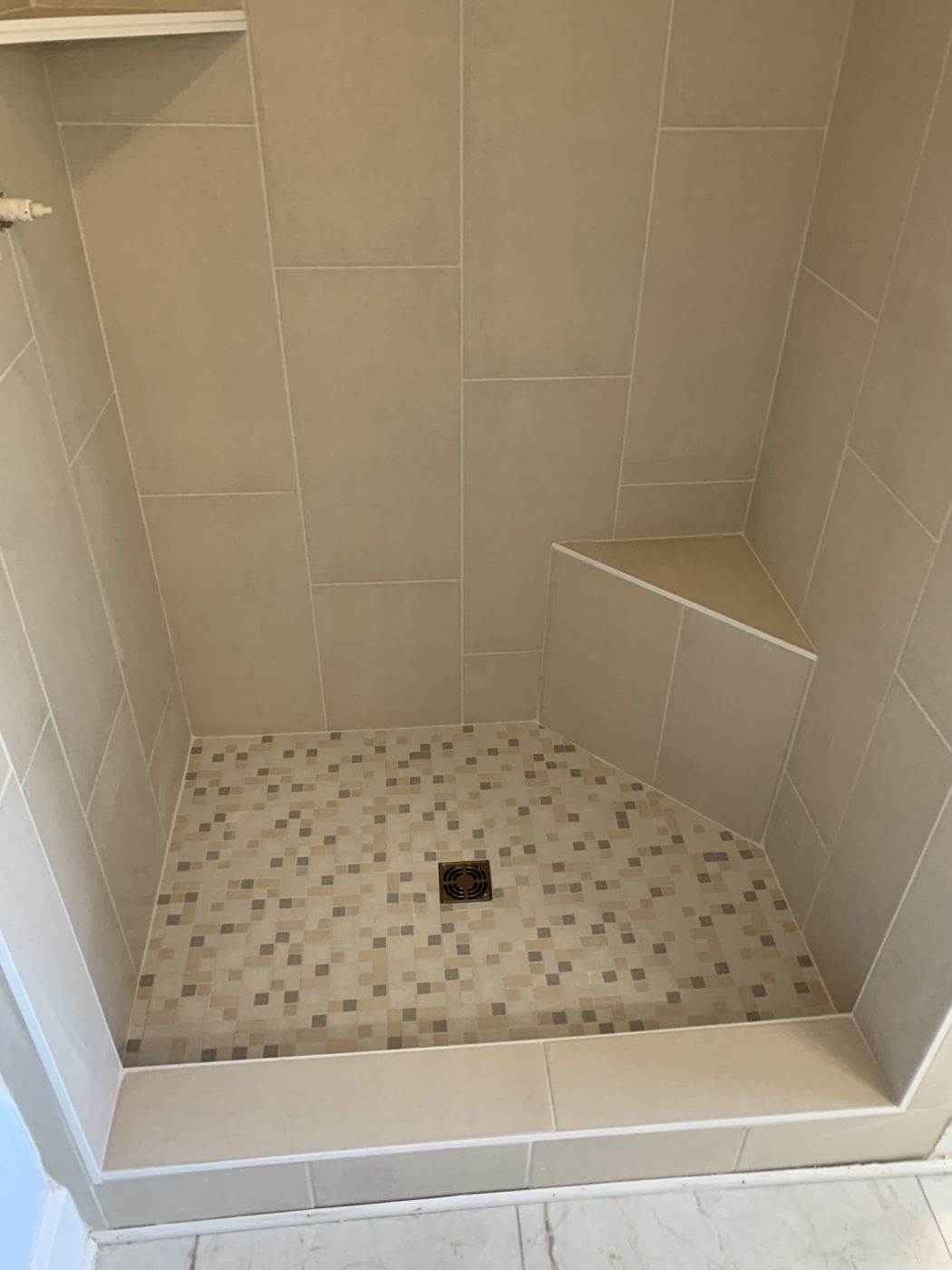 Tiled shower stall with pebble mosaic base and built-in bench