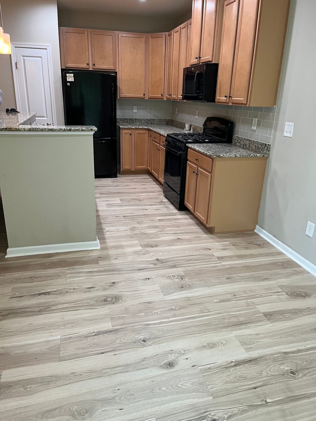 Kitchen with light oak luxury vinyl plank flooring and maple cabinetry