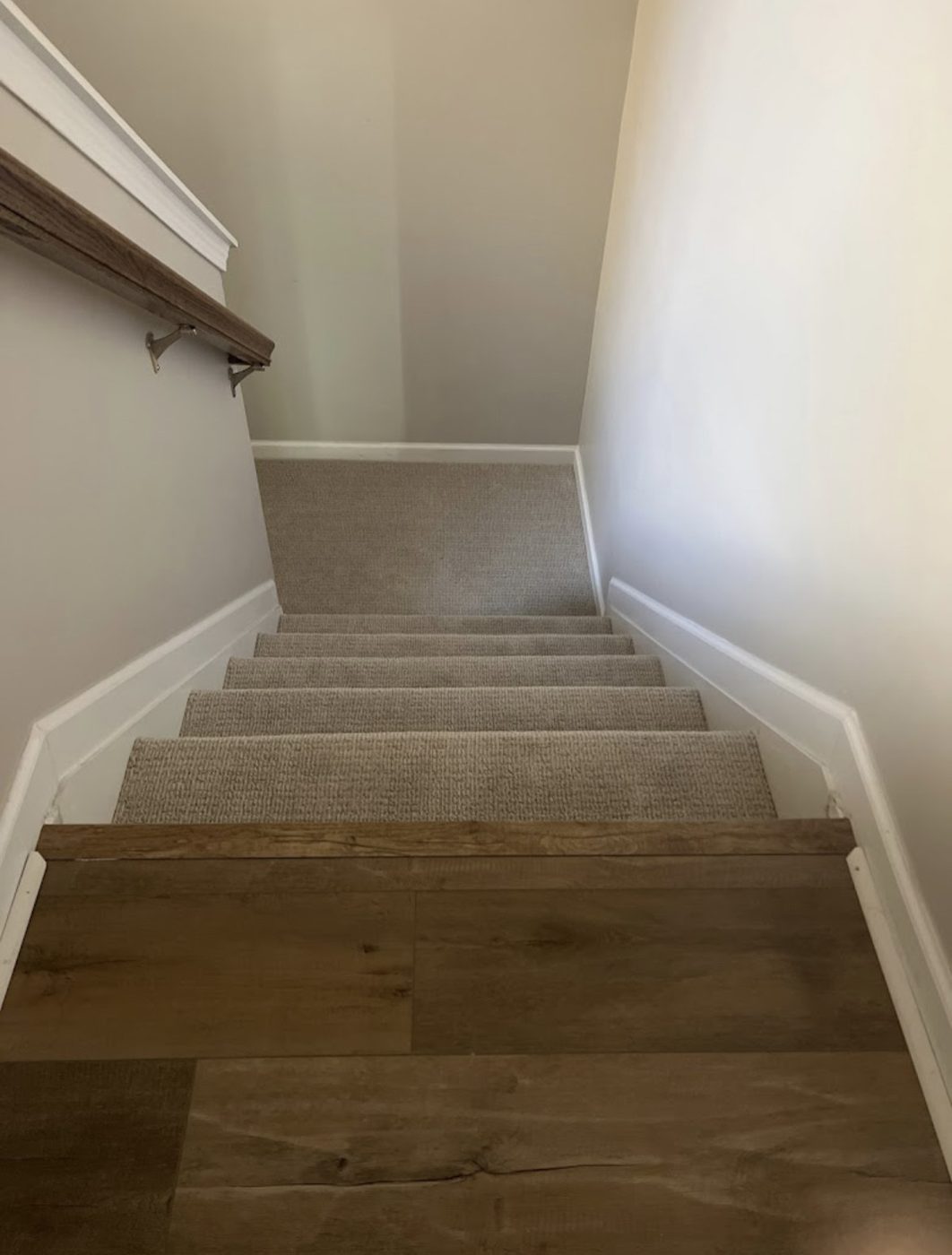 Carpeted staircase meeting a hardwood landing