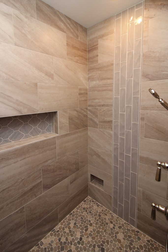 Marble-look tile shower with vertical mosaic accent strip